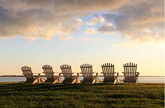 six adirondack chairs sitting by the sea